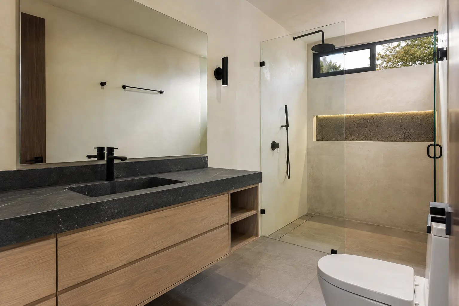 Baño remodelado con cancel de vidrio, madera y grifería negra